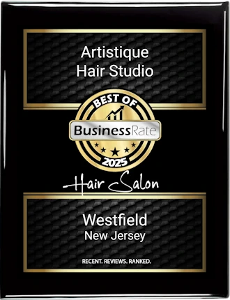 A black and gold award plaque for "Artistique Hair Studio" recognizing them as "Best of BusinessRate 2025 Hair Salon" in Westfield, New Jersey, based on recent reviews and ranking.
