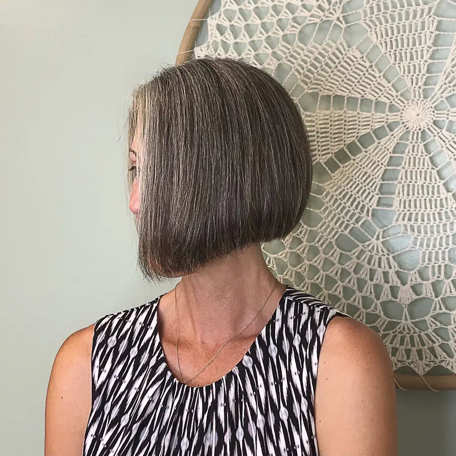 A woman with a short, sleek, silver-grey bob haircut, shown from a side angle.